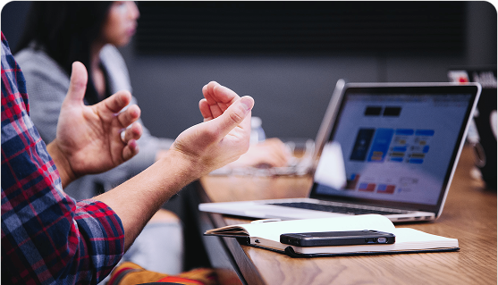 Person gesturing during a business meeting with laptop